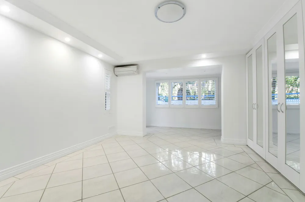Before: an empty bedroom with a white tile floor, an air conditioner and a window alcove