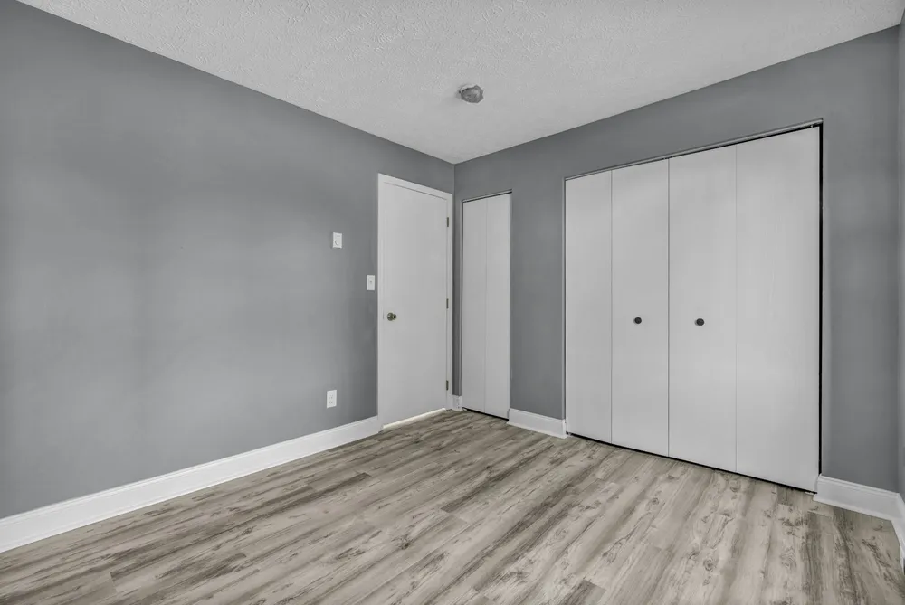 Before: an empty bedroom with a grey accent wall, a white door and white sliding closet doors