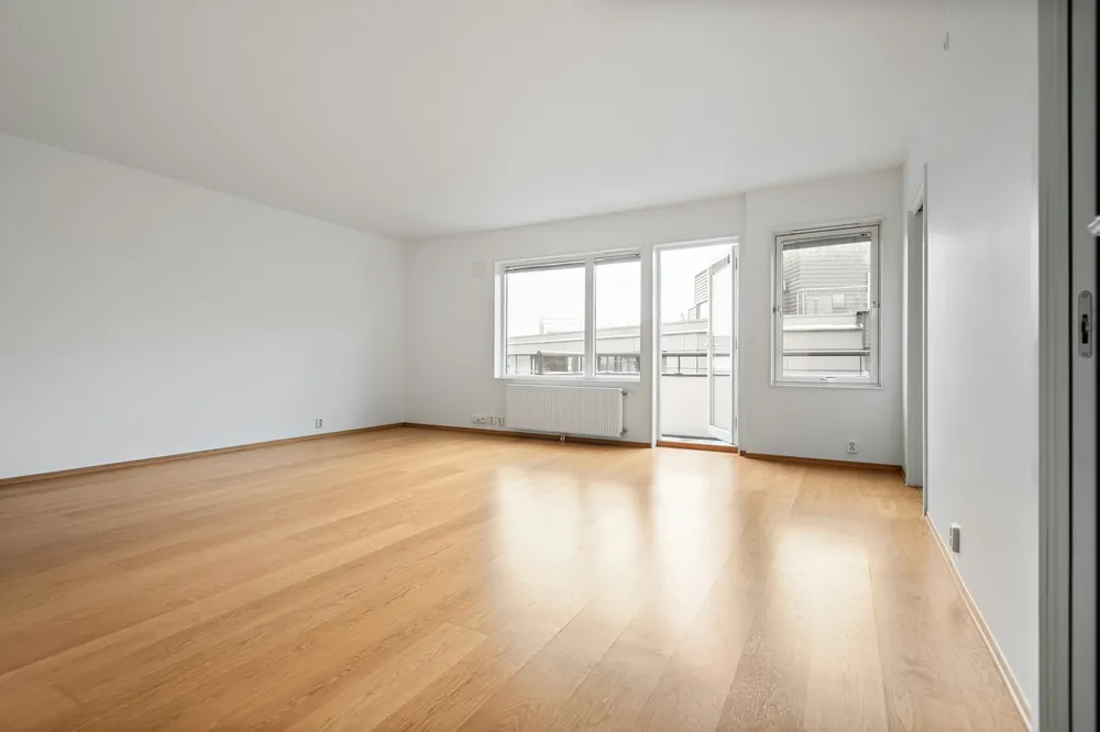 Before: a bright empty living room with a light oak floor, white walls and a balcony door