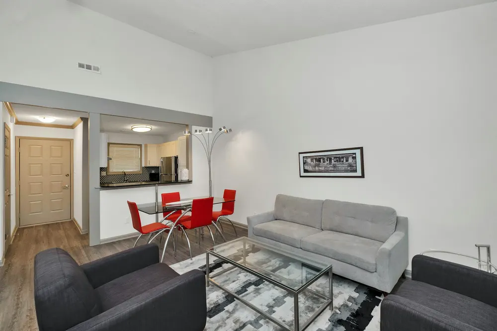 Before: a white living room with a grey sofa and red dining chairs
