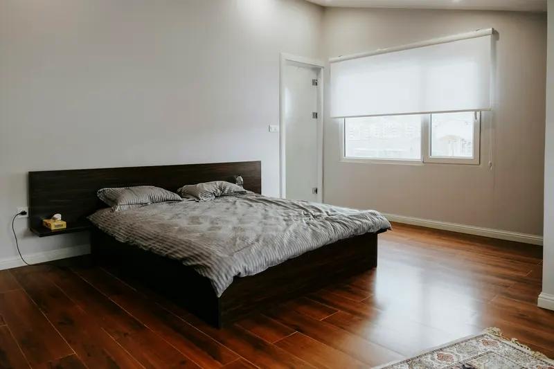 Original bright bedroom photo with a dark wood bed and a large window