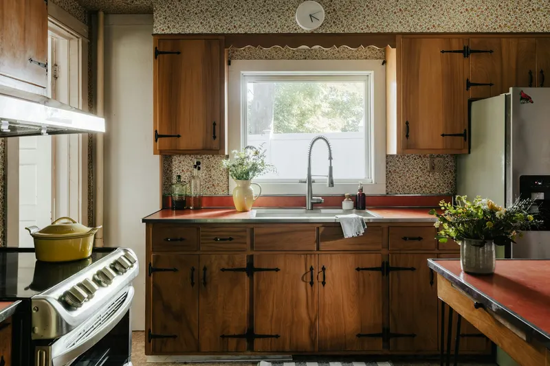 Original kitchen with dark wood cabinets, red counters and patterned wallpaper