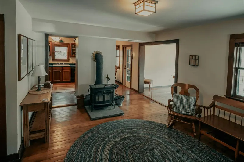 Original living room with a wood stove, a braided rug and wooden chairs