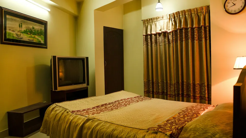 Before: a bedroom with yellow walls, an old TV, a curtained window and a patterned bedspread
