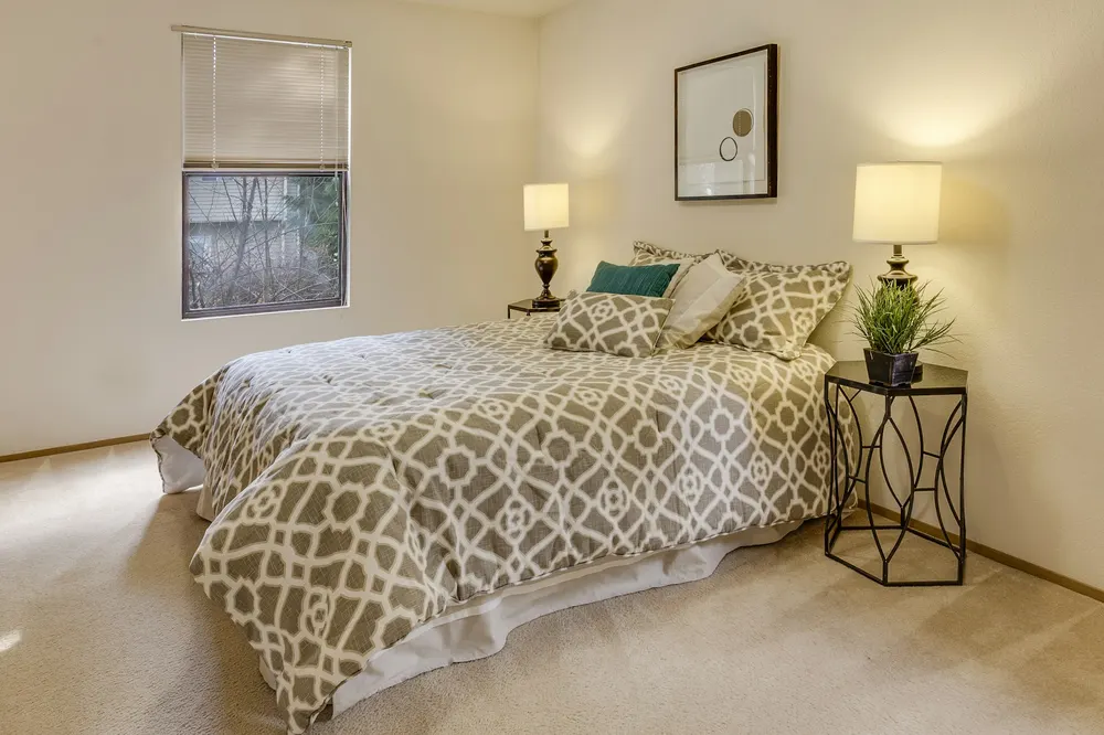 Before: a carpeted bedroom with bold patterned bedding and two lamps