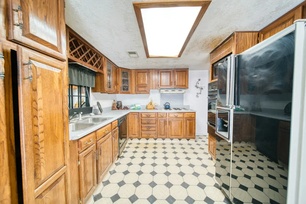 Before: a 1990s kitchen with honey oak raised-panel cabinets and a black and white tile floor