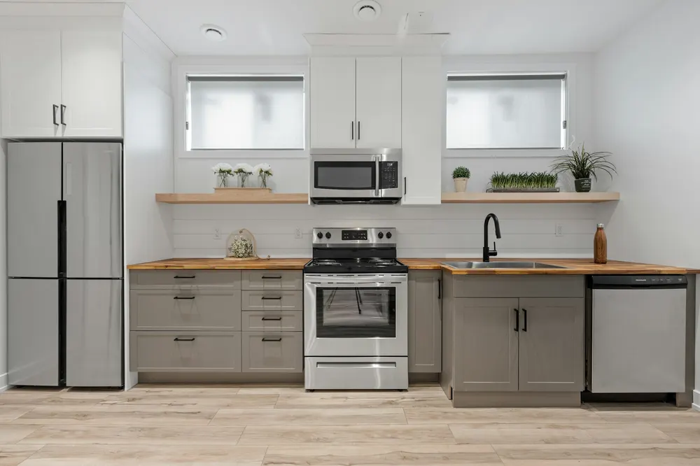 Before: a white and grey kitchen with shaker cabinets and stainless appliances