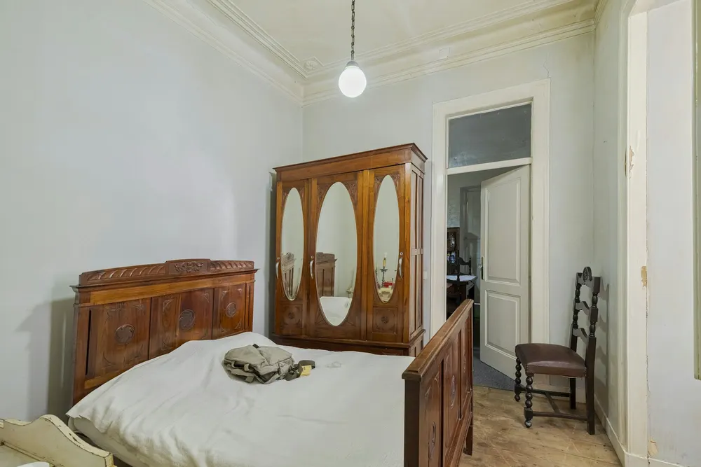 Before: a bedroom with a dark carved antique bed and an oval-mirror wardrobe