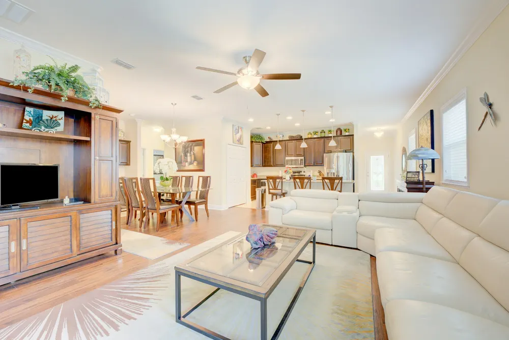 Before: an open-plan living room with a large wood TV cabinet, cream sofas and a dining area