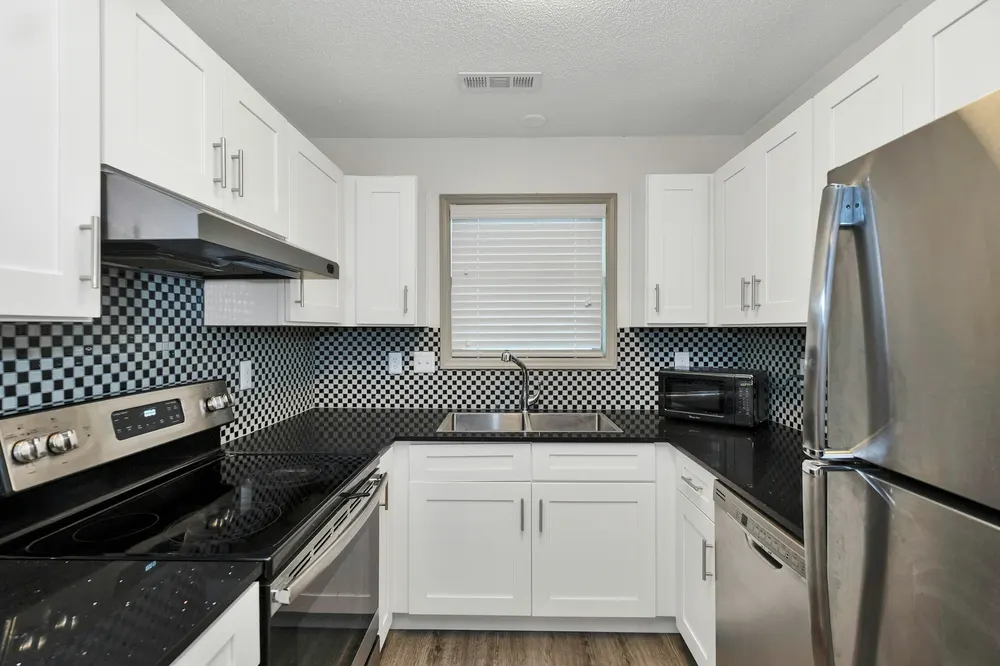 Before: a white kitchen with black granite counters and a black and white mosaic
